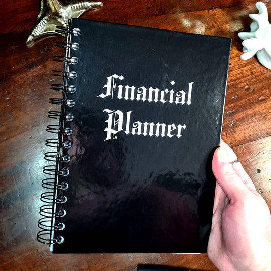 The cover of the Financial Planner by Gothic Office. It's glossy black with white gothic font saying Financial Planner.